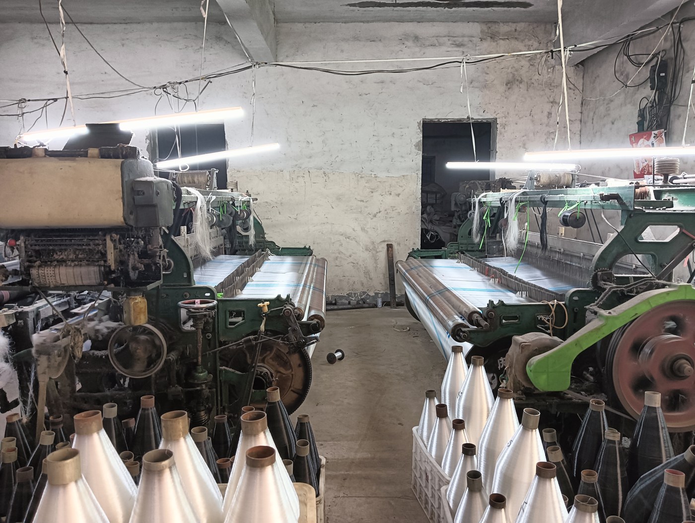 White agricultural mesh fabric being woven on factory looms for protection bag production